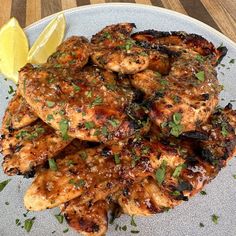 a plate full of chicken covered in sauce and garnished with parsley next to a lemon wedge