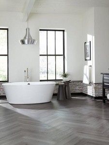 a large white bath tub sitting inside of a bathroom next to two black framed windows