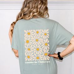 Consider the Wildflowers Retro Christian Comfort Colors Shirt Christian Wildflowers Shirt for Friend Christian Gift Religious Concert Tee Blend fashion and faith with this Comfort Colors tee featuring a retro style flower graphic and the words "Consider the Wildflowers" from Luke 12:27.  Size up for a cute trendy oversized Christian aesthetic! Available in blue jean, crunchberry, melon, blue spruce, violet, and bay. ✿ The With A Wildflower mission is to give God the glory and give back through a Green Daisy Print Summer Top, Green Daisy Print Top For Summer, Summer Green Daisy Print Top, Green Letter Print Shirt For Spring, Spring Floral Graphic Print Top, Spring Daisy Print Short Sleeve Tops, Summer Daisy Print Short Sleeve Tops, Relaxed Fit Daisy Print Tops For Summer, Spring Sunflower Print T-shirt