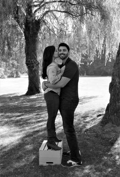 a man and woman holding a baby under a tree