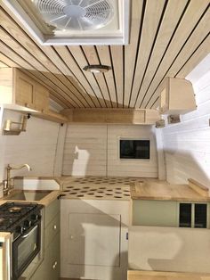 the inside of a small kitchen with wood flooring and ceiling fan above the stove