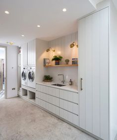 a washer and dryer in a room with white cabinets on the wall next to each other