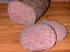 two slices of meat sitting on top of a wooden cutting board