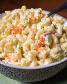 a white bowl filled with macaroni salad on top of a green table