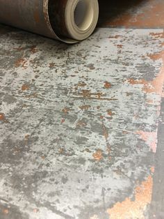 a roll of metallic foil sitting on top of a metal flooring sheet with rusted paint