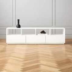 a white entertainment center with two black vases on top and one brown shoe in the bottom