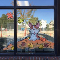 a glass window with a dog in the fall leaves