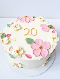 a white cake with pink flowers and the number 20 on it's side is shown