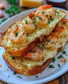 two pieces of bread with shrimp and cheese on them sitting on a white plate next to some parsley