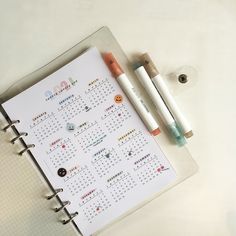 two pens are sitting on top of a calendar