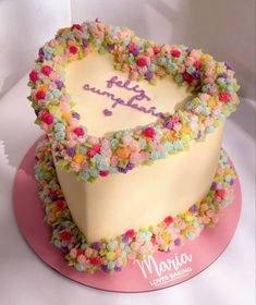 a heart shaped birthday cake with flowers on the top and happy birthday written in frosting