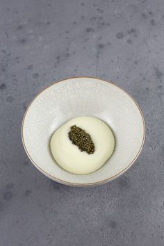 a white bowl filled with food sitting on top of a gray counter next to a knife