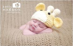 a baby wearing a crocheted giraffe hat laying on top of a blanket