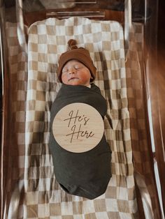 a baby is sleeping in a clear plastic box with a wooden sign that says, it's here