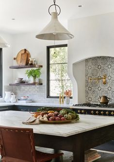 a bowl of fruit is on the table in this kitchen with an oven and sink