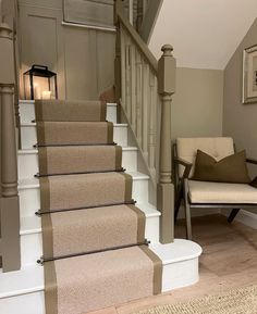 a set of stairs leading up to a living room with beige carpet and pillows on it