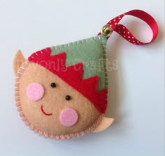 a felt ornament with a red and green hat on it's head