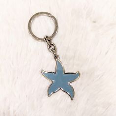 a blue starfish keychain on a white fur background