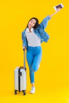 a young woman is posing with her suitcase and holding a book in one hand while smiling at the camera