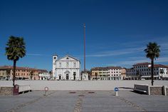 an empty square with palm trees and buildings in the background