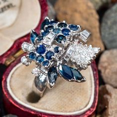 This stunning vintage cluster cocktail ring is accented with six (6), prong set, marquise mixed cut natural blue sapphires, fourteen (14), bead set, round mixed cut natural blue sapphires, five (5), prong set, round brilliant cut diamonds, nine (9), channel set, baguette cut diamonds and twenty-two (22), prong set, round single cut diamonds. The ring measures 22.6mm at the top, rises 15.7mm above the finger, tapering to 3.5mm wide and 1.0mm thick at the base of the shank. This ring is currently a size 4.75. Antique Cocktail Ring, Diamond Jewelry Designs, Blue Sapphire Diamond, Bead Set, Baguette Cut Diamond, Natural Blue Sapphire, Channel Set, Baguette Cut, Diamond Cluster