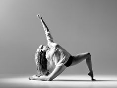 black and white photograph of a woman doing a yoga pose on the floor with her arms in the air