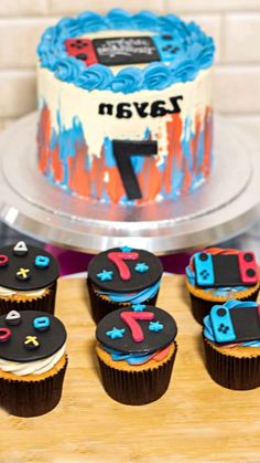 cupcakes are arranged in front of a birthday cake with the number seven on it