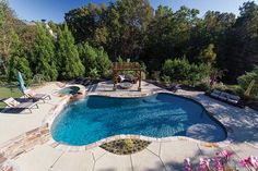 an outdoor swimming pool surrounded by trees and lawn furniture, with chairs around the pool