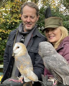 a man and woman holding two birds in their hands