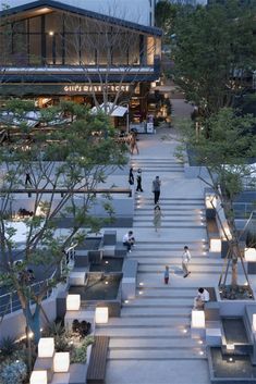 people are walking up and down the stairs in front of an office building at dusk