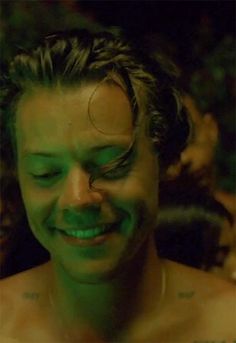 a man with green paint on his face is smiling at the camera while he looks down