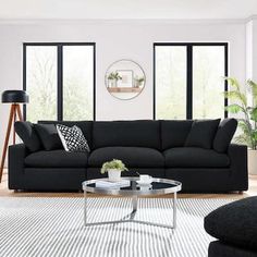 a living room with black couches and white rugs