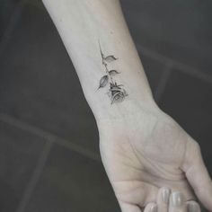 a woman's hand with a small rose tattoo on it