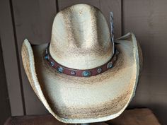 The Cassidy starts with a soft palm hat body that has been flame distressed so it looks like it has already been broken in. The brim is approximately 4" and the crown is 5". There is a wire in the brim so you can shape it however you want. The leather hatband is new rein leather and has lots of Southwestern Conchos. The back of the band has a deer antler bead for accent. Stampede strings are attached to hat which will make it a great hat for riding or on those windy days. Finished with an Owl fe Adjustable Distressed Hats For Country Events, Distressed Adjustable Hats For Country Events, Adjustable Distressed Brimmed Hat, Adjustable Flat Crown Straw Hat For Rodeo, Adjustable Straw Hat With Flat Crown For Rodeo, Distressed Adjustable Flat Brim Hat, Rustic Distressed Adjustable Hat, Distressed Flat Brim Hat With Adjustable Fit, Custom Curved Brim Straw Hat For Rodeo