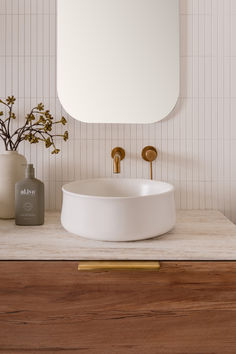 a white sink sitting on top of a wooden counter next to a vase with flowers