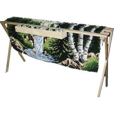 a table with a painting on it that has trees and water in the middle, along with two wooden legs