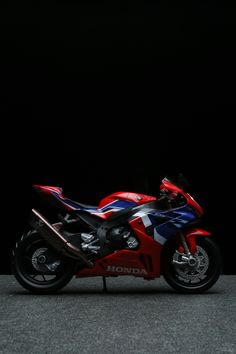 a red, white and blue motorcycle parked in the dark