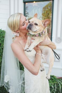 a woman in a wedding dress holding a dog