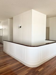 an empty living room with hard wood flooring and white cabinets on either side of the wall