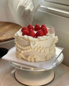 a cake with white frosting and raspberries on top