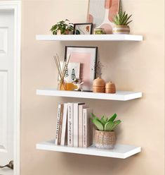 three white shelves with plants and books on them