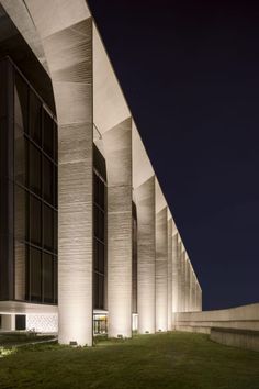 the exterior of a building lit up at night with lights shining on it's sides