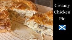 a chicken pie is cut in half on a cutting board with the words creamy chicken pie above it