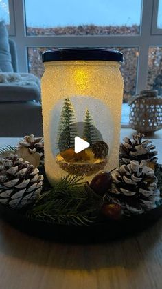 a mason jar filled with pine cones on top of a table next to a window