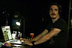 a man sitting at a desk in front of a laptop computer with a light on