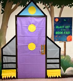 a purple door with yellow and blue decorations on the front is decorated like a rocket ship