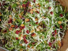 a salad in a wooden bowl with nuts and cranberries on top is ready to be eaten