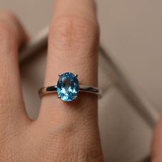 a woman's hand with a ring on it and a blue stone in the middle