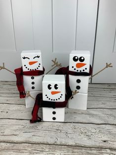 four snowmen made out of toilet paper sitting on top of a wooden floor next to each other