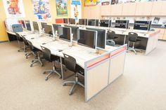 an office cubicle with multiple computer screens and desks, all in different colors